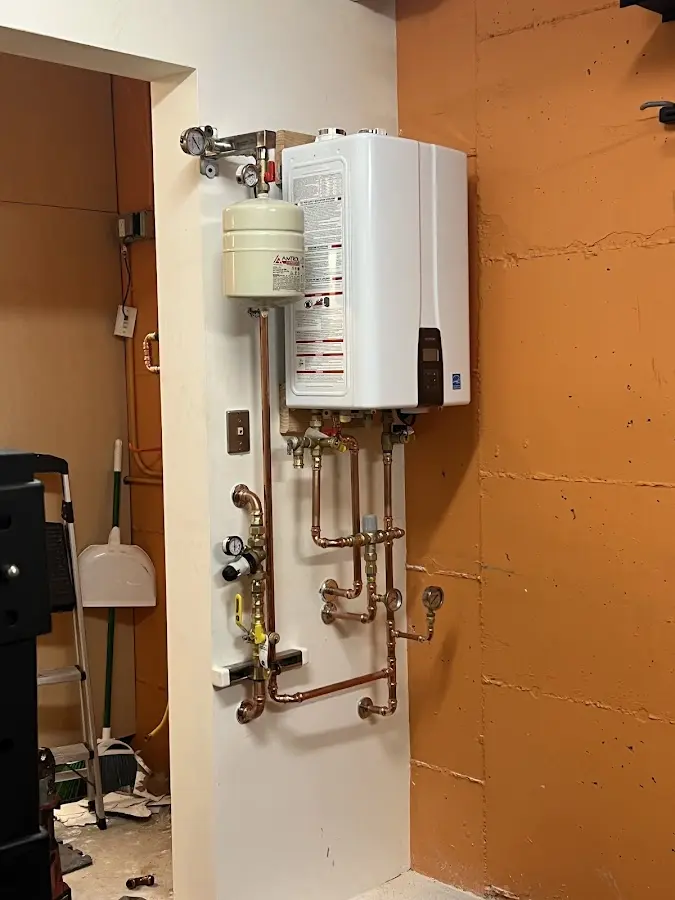 Plumbing technician inspecting water heater connections in Greene